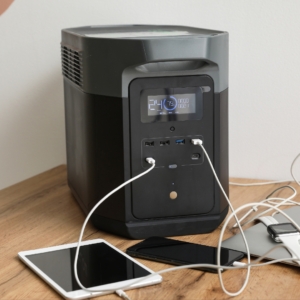 Portable power station on a desk with smart devices plugged into it.