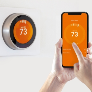 Person controlling a smart thermostat from their smartphone.