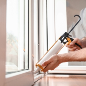 Person caulking windows in a home.