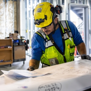 Electrician reads blueprints inside a commercial property.