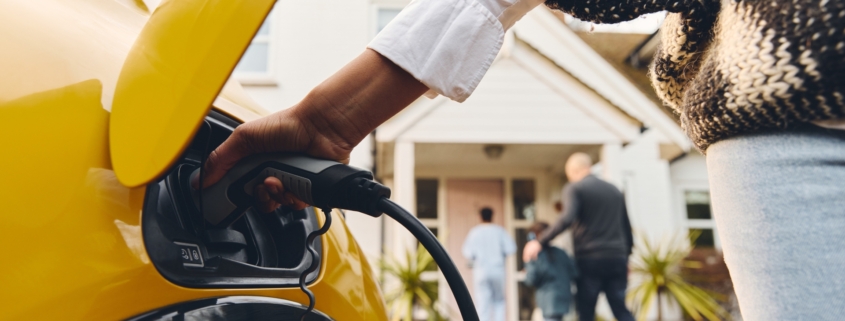 Woman charges her electric vehicle outside of her home.