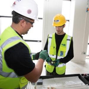 Two electricians reviewing blueprints.