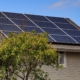 Solar panels on the roof of a home with tan siding.