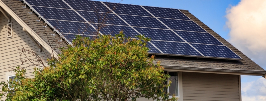 Solar panels on the roof of a home with tan siding.