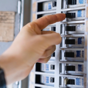 Person turning on electrical panel switches.