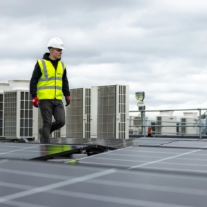 Commercial electrical worker installing generators on top of a building.