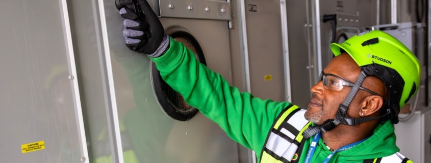 Commercial electrician in green hard hat and safety vest.