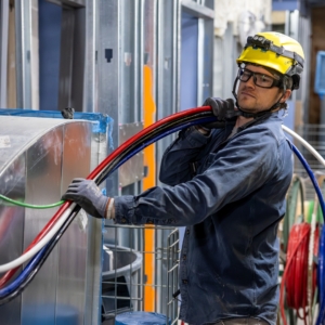 Commercial electrician in safety gear holds wiring and conduit.