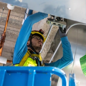 Commercial electrician updating wiring in the ceiling of a factory.