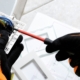 Electrician wears safety gloves while fixing a home electrical socket.
