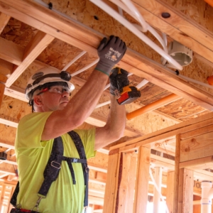 Residential electrician affixes wiring to a home's ceiling.