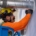 Male commercial electrician with safety goggles, yellow hardhat, blue gloves, and orange shirt stands on blue ladder while fixing a warehouses conduit system.