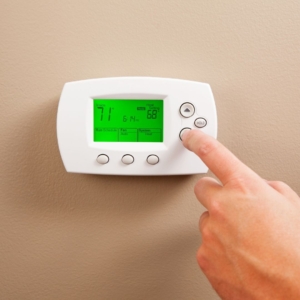 Finger touching a button on a white smart thermostat set to 68 degrees.