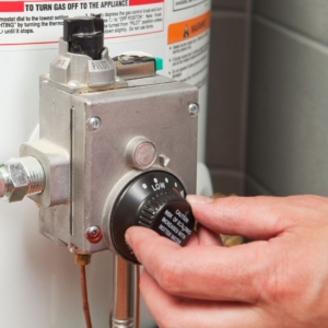 Hand adjusting knob on water heater.