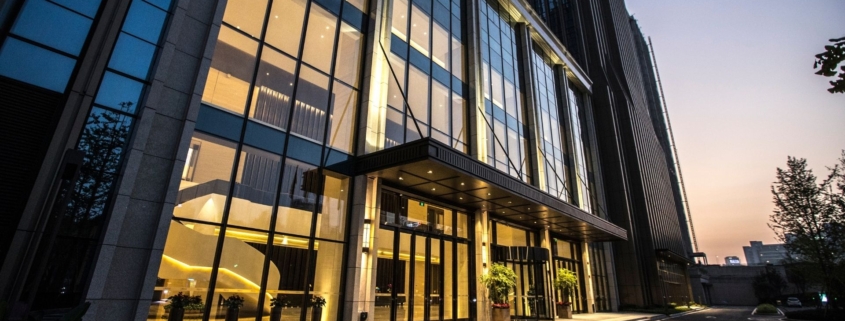 Exterior of office building at night with lights on and large windows.