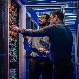 Two commercial electricians in a server room working on wiring.