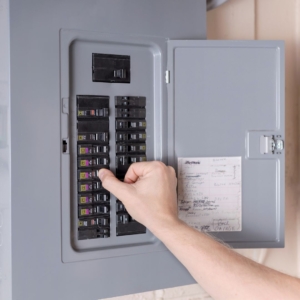 Person turning off a switch on their home's electrical panel.