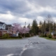 Homes in a residential neighborhood with grey road and storm clouds overhead.