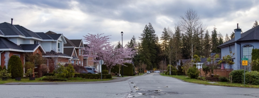 Homes in a residential neighborhood with grey road and storm clouds overhead.