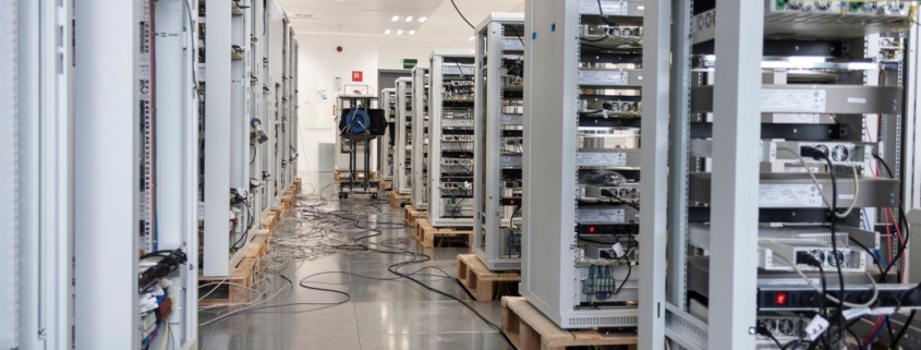 Multiple grey server towers arranged in rows inside an industrial data center.