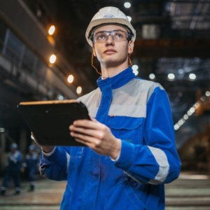 Industrial worker with hard hat, blue uniform, and clipboard.