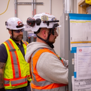 Two electrical contractors work on upgrading an electrical panel.