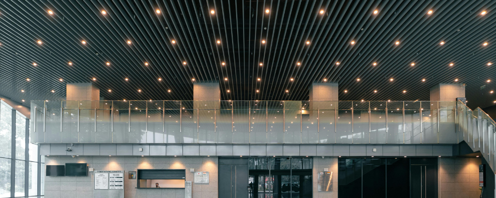 Contemporary office building with overhead lights and a stairway made of glass panels.