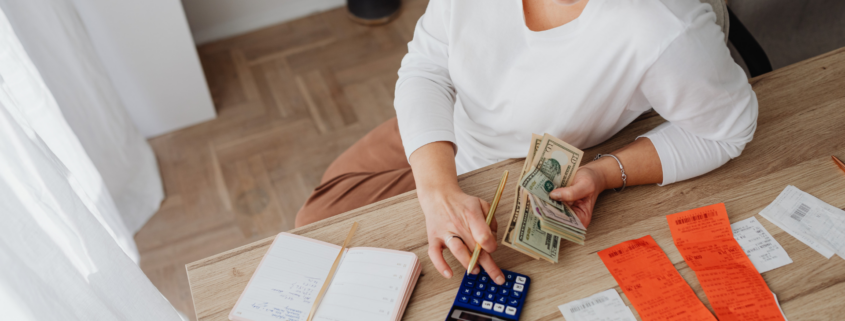 Woman in white shirt pays bills while sitting at her desk.