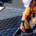 An electrical worker installing solar panels on a roof.