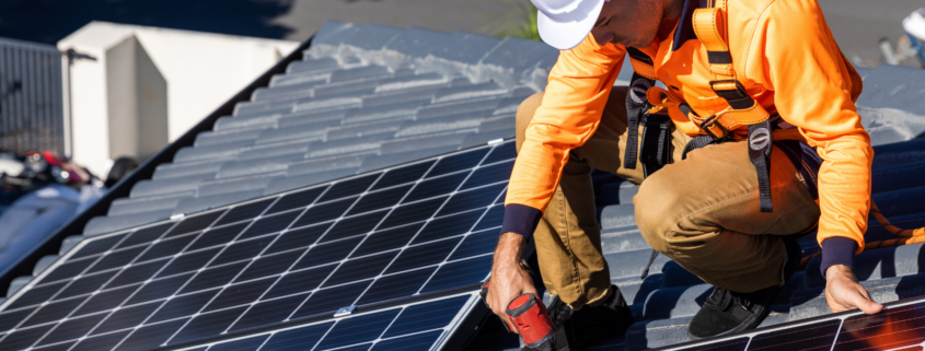 An electrical worker installing solar panels on a roof.