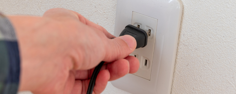 A hand inserting a plug into an outlet.