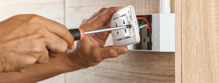 A close-up image of a person using a screwdriver to install a GFCI outlet.